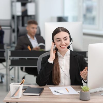 Saleswoman talking to client via headset at desk in office