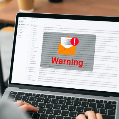 Hand using laptop with shows a warning screen of new email notifications, hack password and personal data. Concept of cyber crime