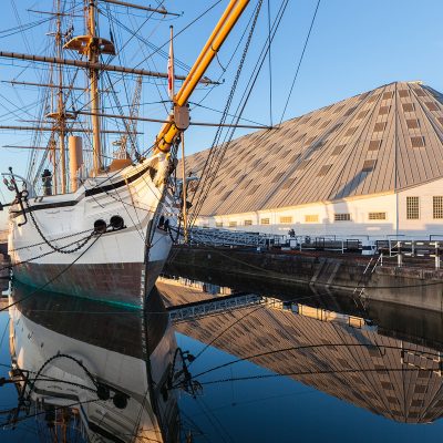 Chatham Dockyards with an white old sailing ship in the dock next to a hanger building