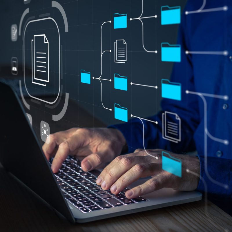 View of someone using a laptop with digital transformation of IT processes made visible above their hands, as they type.